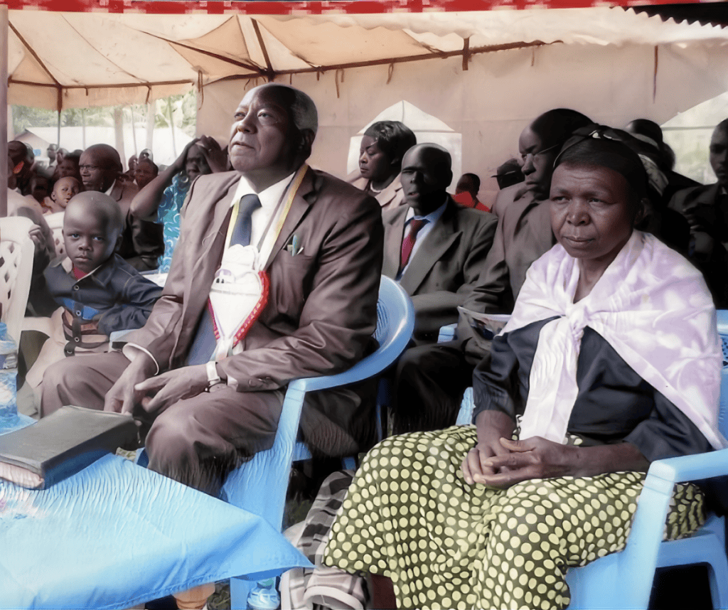 Pastor David Shikambi Luvai and his wife Methabel sitting together under a tent at a church event in Kenya.