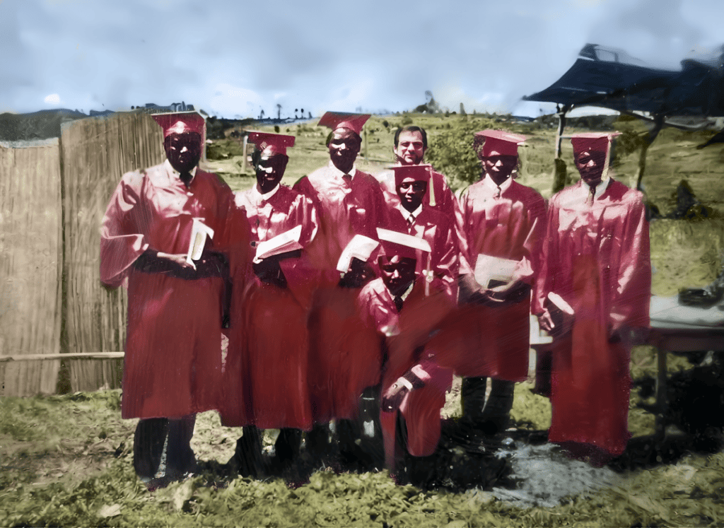 Group of graduates in red gowns and caps holding Bibles, standing outdoors in Kenya.