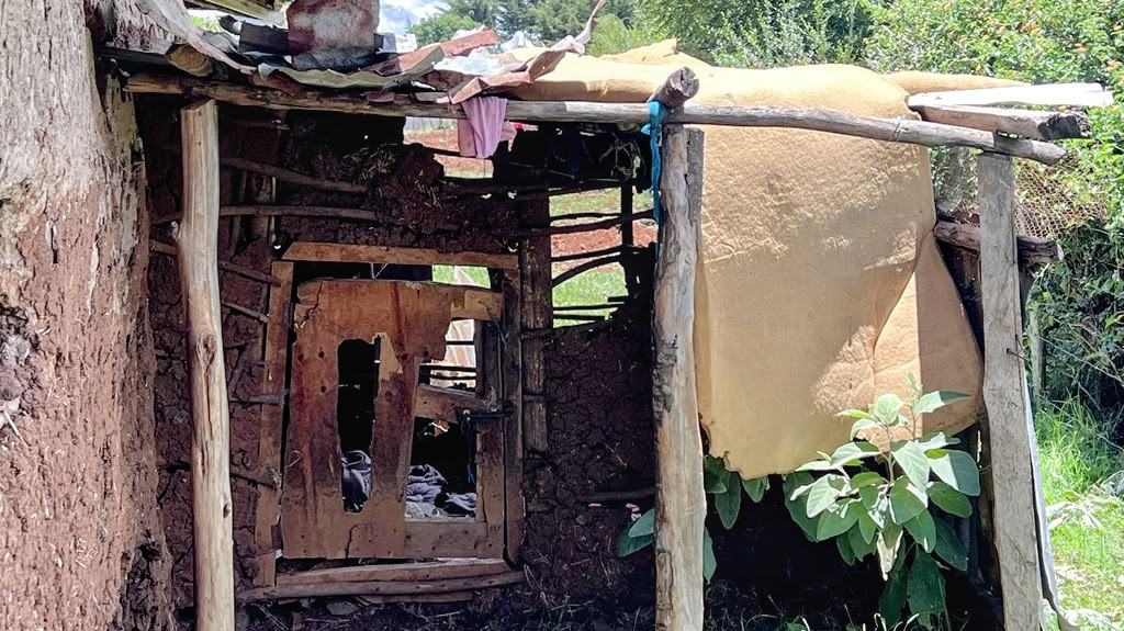 A dilapidated structure with a partially broken door, used as a kitchen.