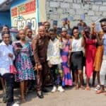 A group of people in the Democratic Republic of Congo holding up their new Bibles outside a church, smiling and celebrating.