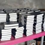 Stacks of Bibles neatly arranged on a table, ready for distribution in the Democratic Republic of Congo (DRC), with boxes labeled "Francophone TOTAL 1459" in the background.