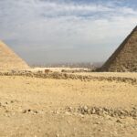 The Pyramids of Giza in the foreground with the city of Cairo in the bacground.